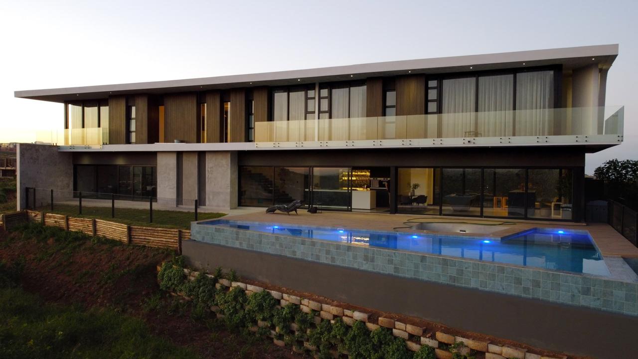 Cantilevered first-floor slab above a pool terrace at dusk