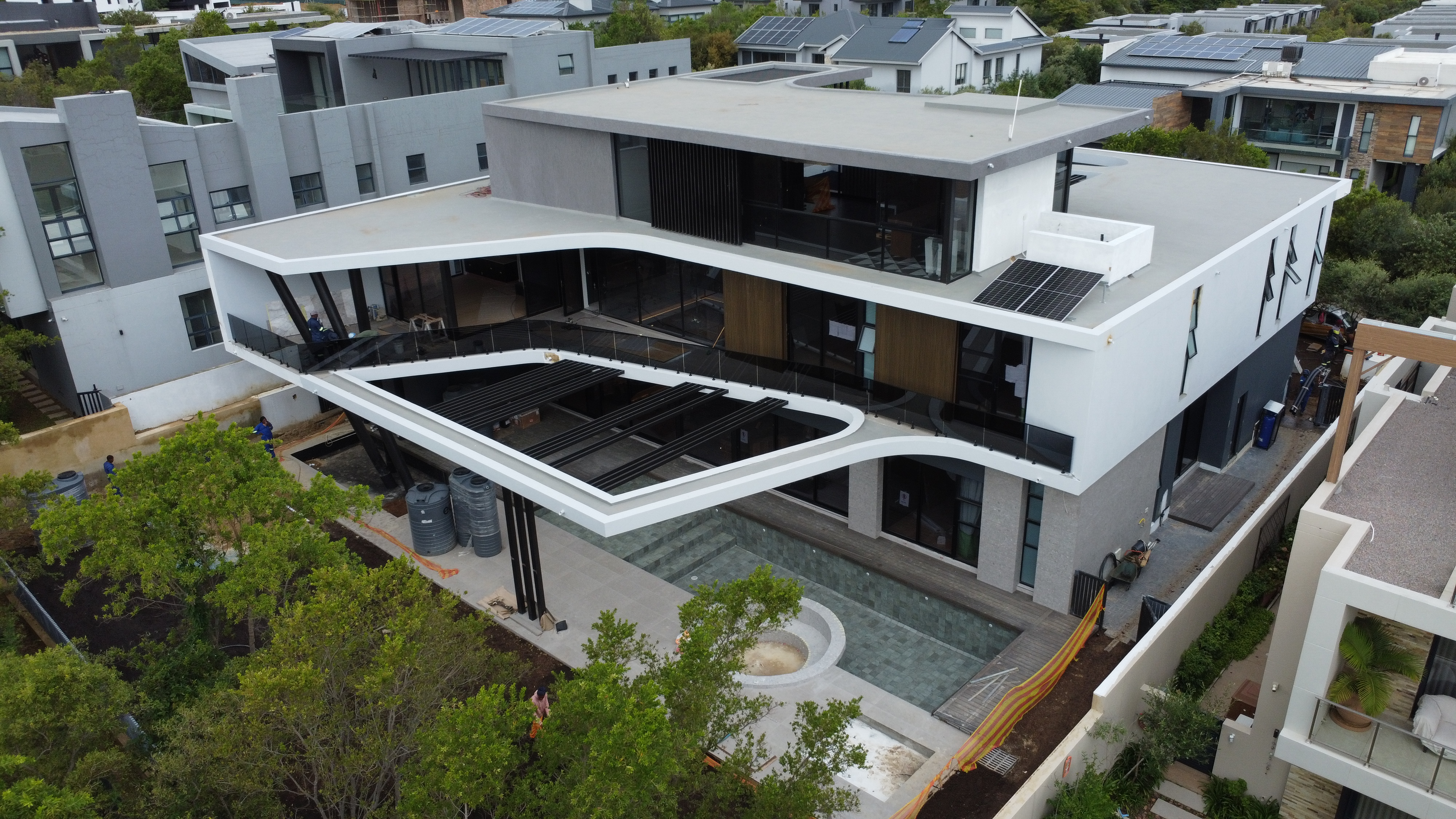 Aerial of a curved-roofline home with pool and louvre screens