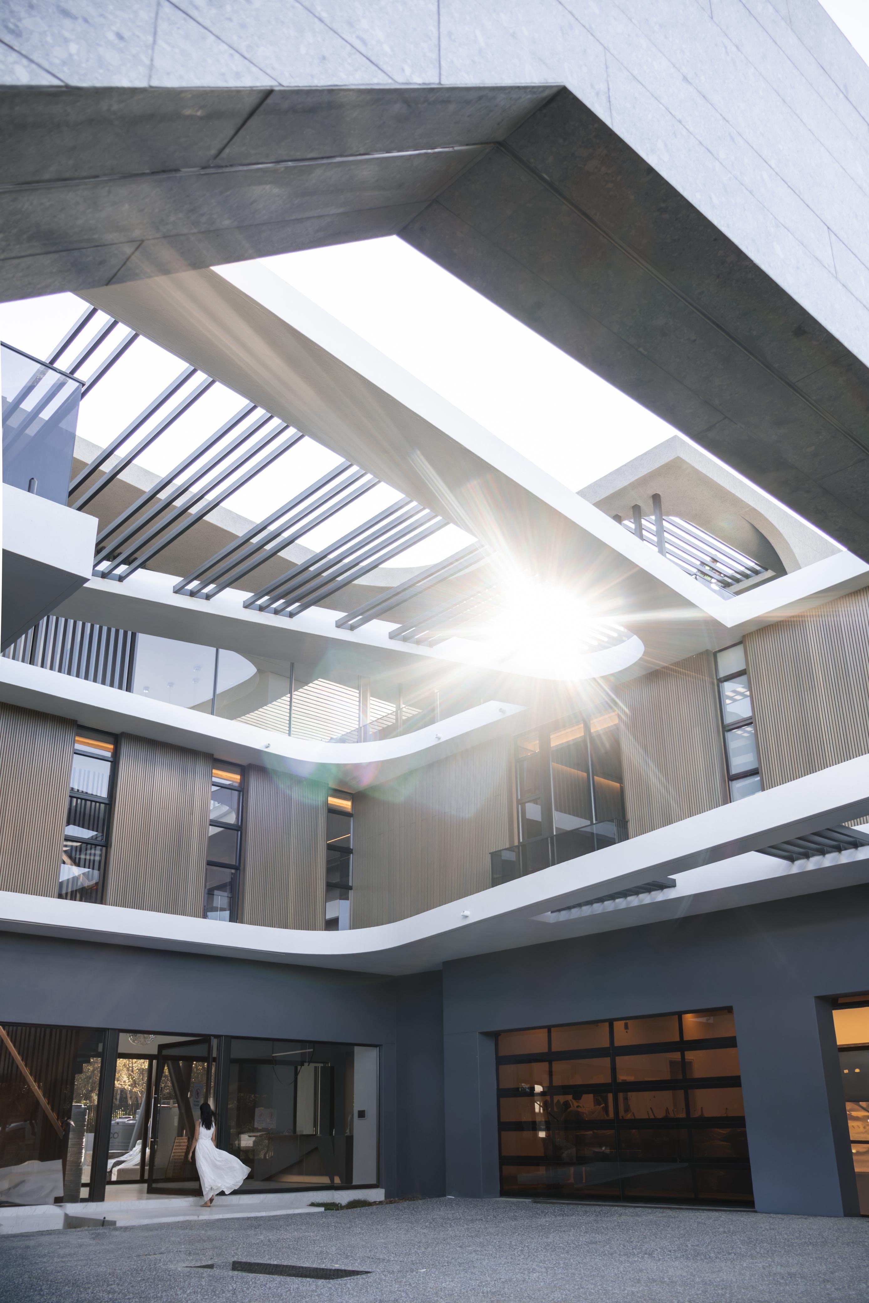Courtyard with a steel pergola and curved soffit cutouts