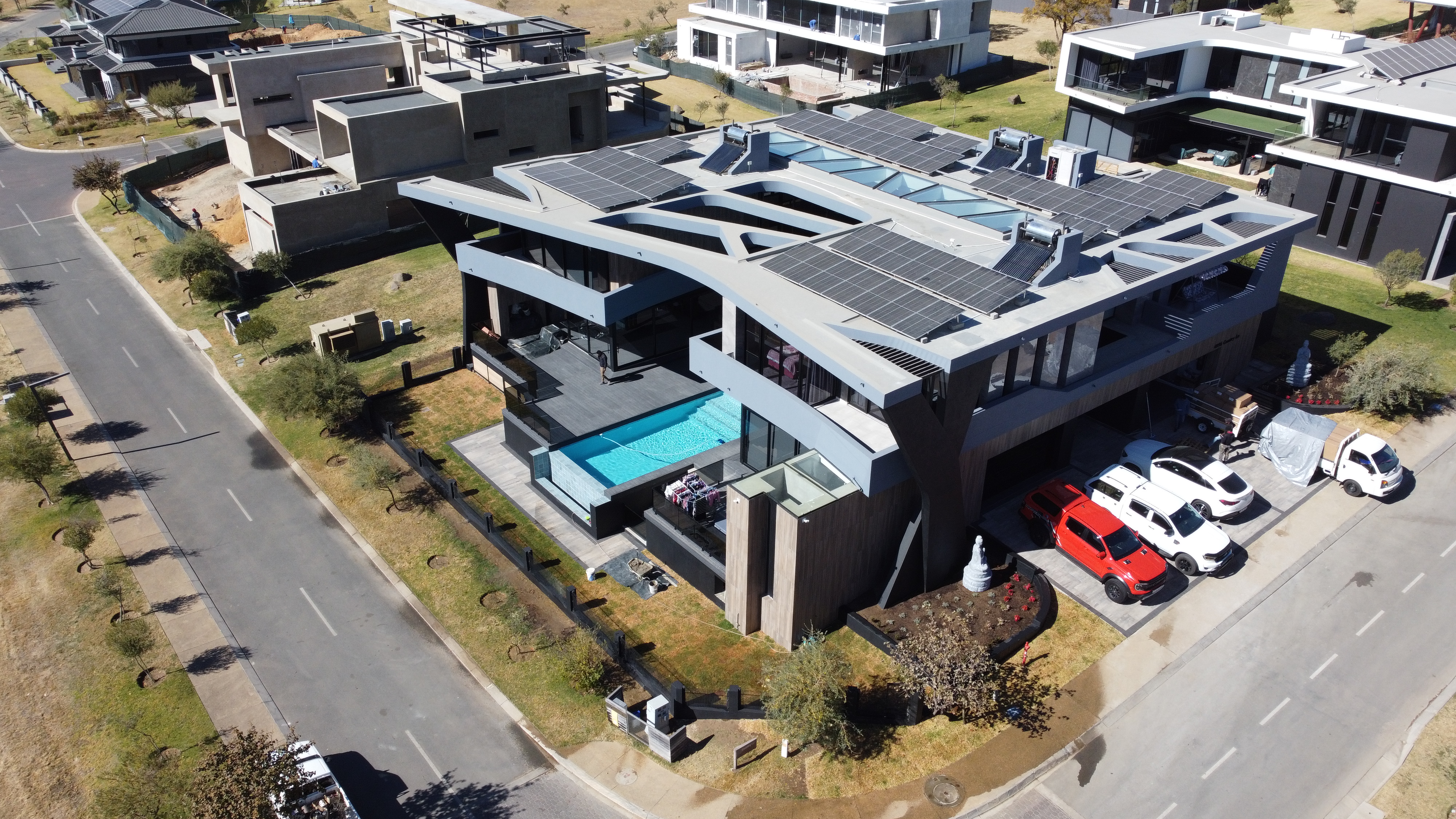 Aerial of a contemporary flat-roof home with solar roof and pool